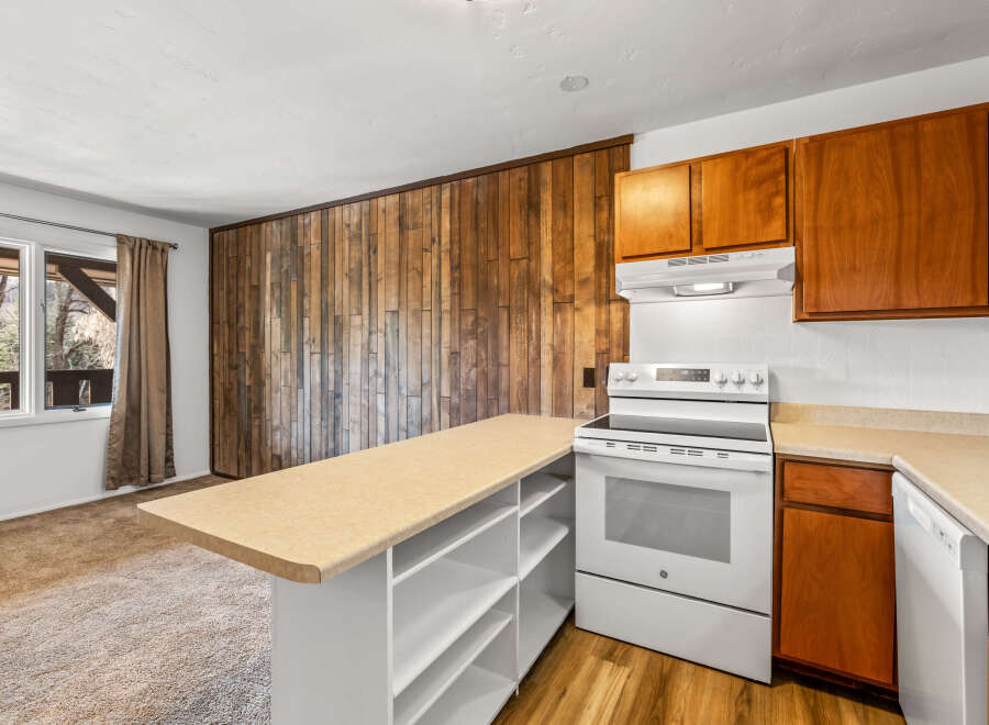 This charming kitchen boasts a unique wooden accent wall, adding warmth and character to the space.