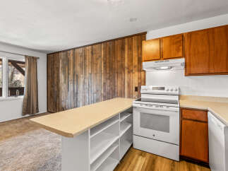 This charming kitchen boasts a unique wooden accent wall, adding warmth and character to the space.
