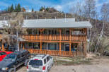 This charming two-story property boasts a rustic design with wooden balconies and a metal roof, offering a blend of mountain living and modern comfort.