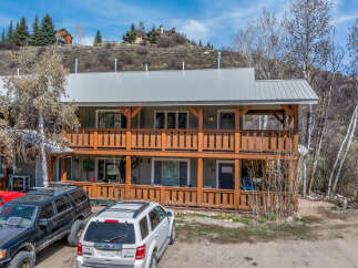 This charming two-story property boasts a rustic design with wooden balconies and a metal roof, offering a blend of mountain living and modern comfort.