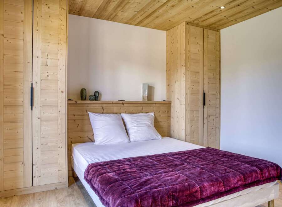 This cozy bedroom features a stunning wooden ceiling and matching built-in wardrobes, creating a warm and inviting atmosphere.