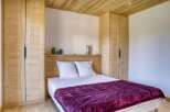 This cozy bedroom features a stunning wooden ceiling and matching built-in wardrobes, creating a warm and inviting atmosphere.