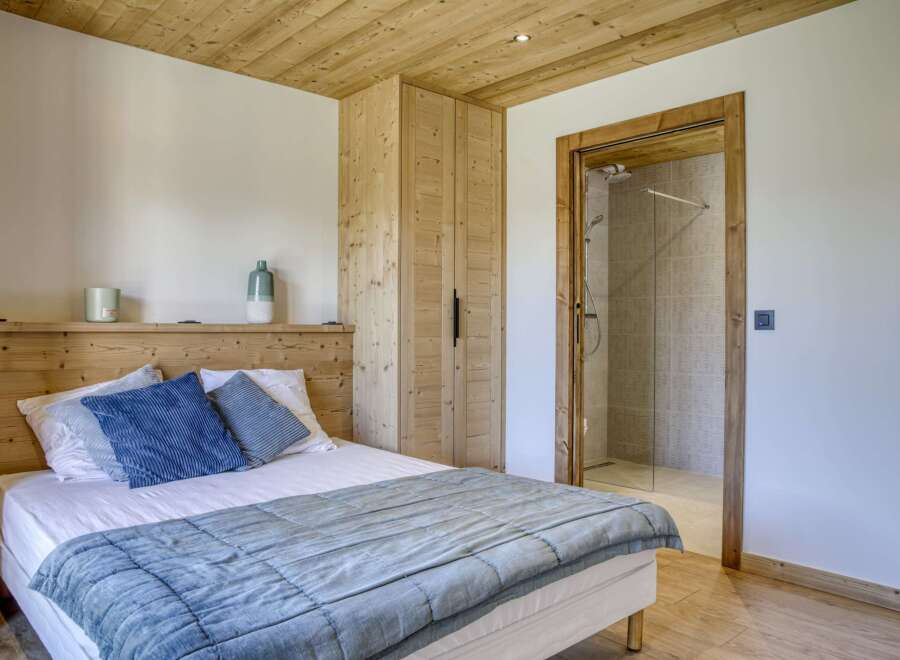 This cozy bedroom features a beautiful wooden ceiling and walls, creating a warm and inviting atmosphere.