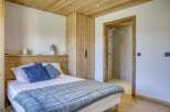 This cozy bedroom features a beautiful wooden ceiling and walls, creating a warm and inviting atmosphere.