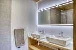 This modern bathroom boasts a sleek design with a double sink vanity and a large, illuminated mirror.