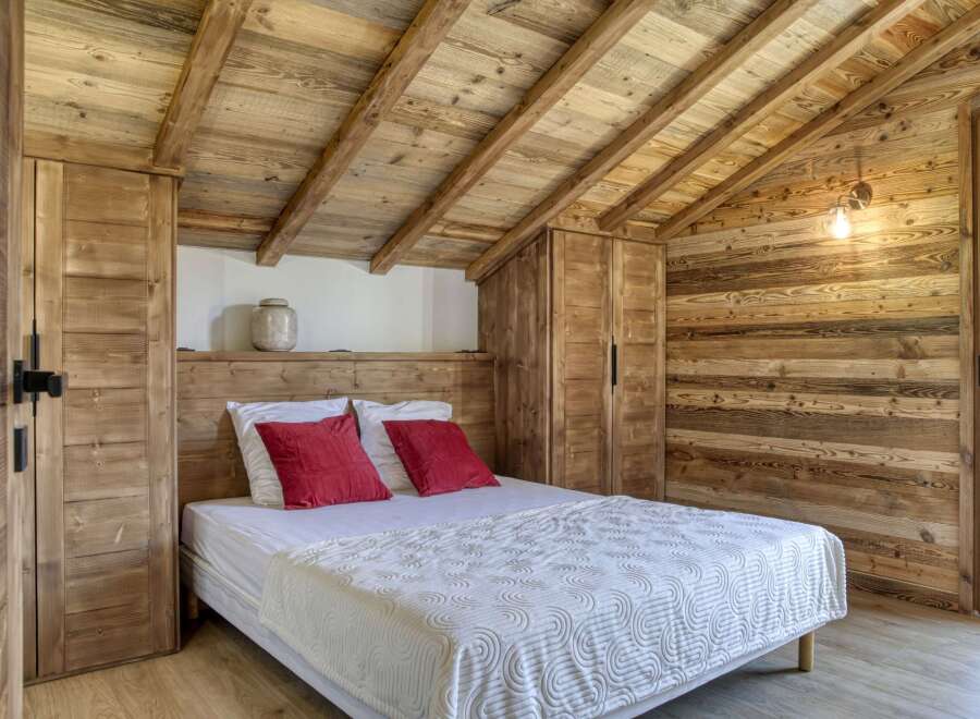This cozy bedroom features rustic wooden walls and ceiling, creating a warm and inviting atmosphere.