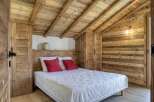 This cozy bedroom features rustic wooden walls and ceiling, creating a warm and inviting atmosphere.
