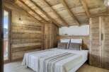 Experience the charm of this cozy bedroom, featuring rustic wooden walls and a sloped ceiling that adds character.