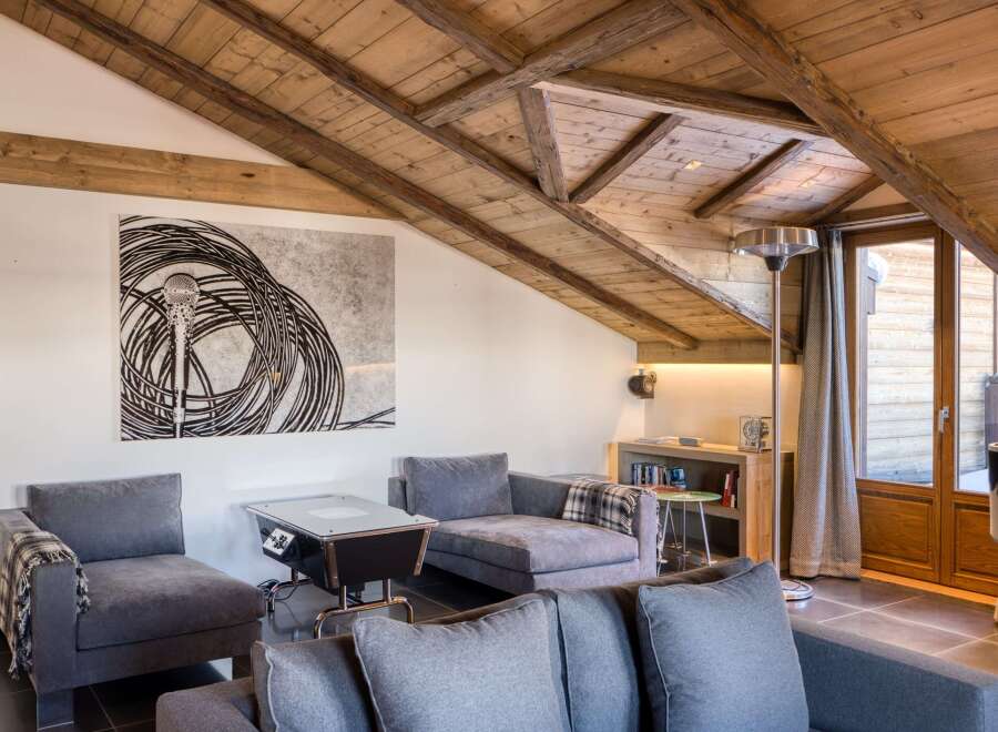 This stunning living room boasts a unique architectural design with a wooden sloped ceiling and exposed beams, creating a warm and inviting atmosphere.