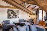 This stunning living room boasts a unique architectural design with a wooden sloped ceiling and exposed beams, creating a warm and inviting atmosphere.
