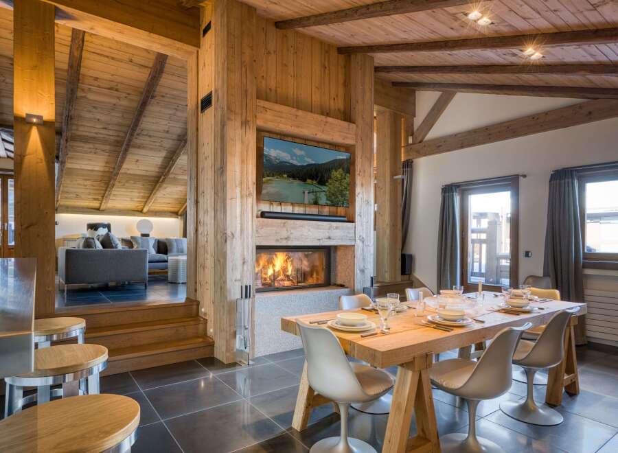 Experience luxury living in this stunning chalet, featuring a cozy fireplace and a modern dining area.