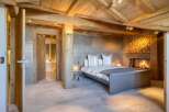 Experience luxury in this stunning bedroom featuring a cozy fireplace and a rustic wooden ceiling.