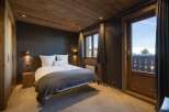 This cozy bedroom features a rustic wooden ceiling and walls, creating a warm and inviting atmosphere.