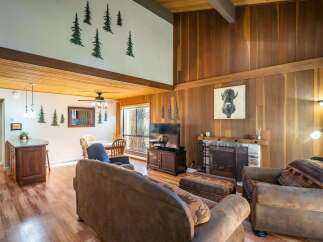Step into this inviting living space, featuring a cozy fireplace and rustic wood paneling that exudes warmth and charm.