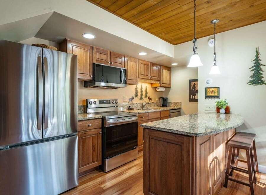 This stunning kitchen boasts stainless steel appliances, including a refrigerator, oven, and microwave, complemented by beautiful wooden cabinetry.