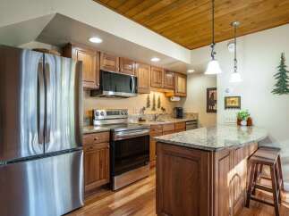 This stunning kitchen boasts stainless steel appliances, including a refrigerator, oven, and microwave, complemented by beautiful wooden cabinetry.