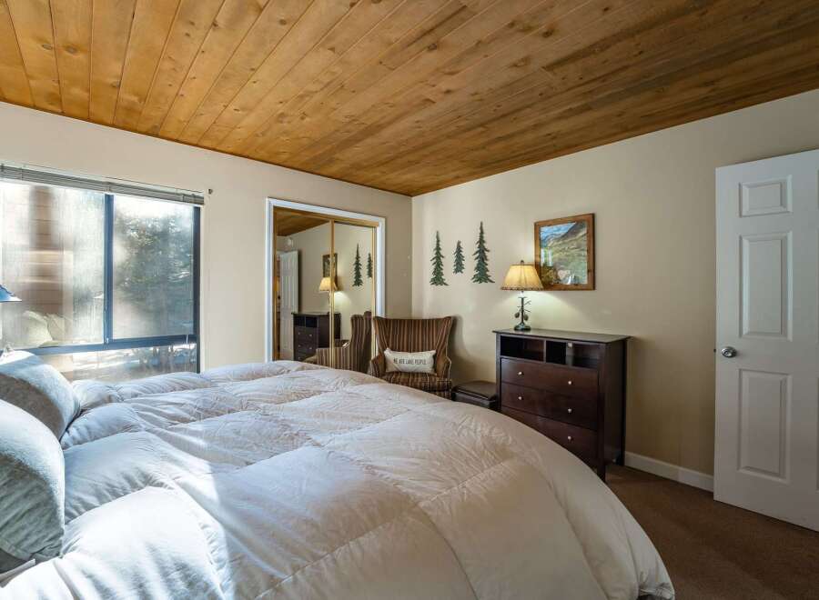 Step into this inviting bedroom, featuring a cozy ambiance with its wooden ceiling and neutral color palette.