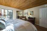 Step into this inviting bedroom, featuring a cozy ambiance with its wooden ceiling and neutral color palette.