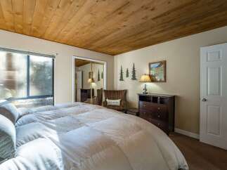 Step into this inviting bedroom, featuring a cozy ambiance with its wooden ceiling and neutral color palette.