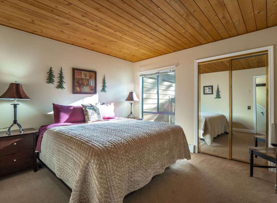 This cozy bedroom features a warm, inviting atmosphere with a wooden ceiling and neutral-toned walls.