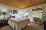 This cozy bedroom features a warm, inviting atmosphere with a wooden ceiling and neutral-toned walls.