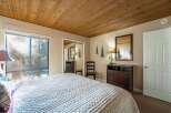 This cozy bedroom features a warm wooden ceiling and a large window that lets in plenty of natural light.