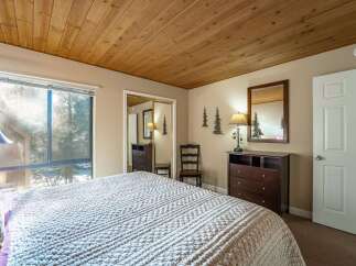 This cozy bedroom features a warm wooden ceiling and a large window that lets in plenty of natural light.