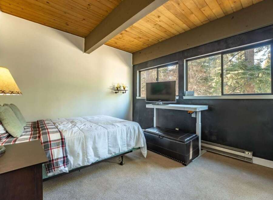 This cozy bedroom features a comfortable bed with a stylish plaid blanket and a warm, inviting ambiance.