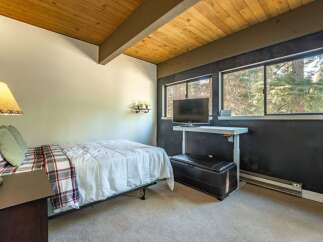 This cozy bedroom features a comfortable bed with a stylish plaid blanket and a warm, inviting ambiance.