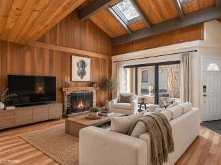 Experience rustic charm in this living room featuring a vaulted wood-paneled ceiling with skylights and exposed beams.