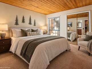 Experience cozy comfort in this inviting bedroom, featuring a plush king-size bed adorned with decorative pillows and a warm, textured throw.