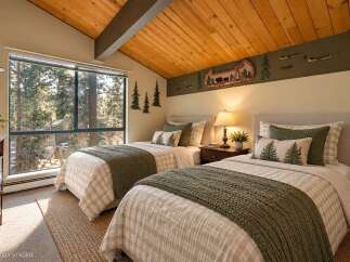 Experience rustic charm in this inviting bedroom, featuring two twin beds adorned with cozy plaid bedding and forest-themed accents.