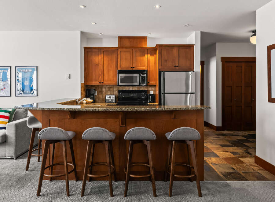 This stunning kitchen boasts beautiful wooden cabinetry, a sleek stainless steel refrigerator, and a convenient microwave.