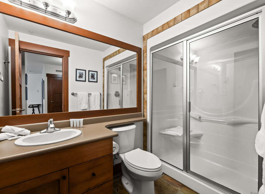 Step into this beautifully designed bathroom, featuring a spacious shower with glass doors and a comfortable seating area.