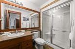 Step into this beautifully designed bathroom, featuring a spacious shower with glass doors and a comfortable seating area.