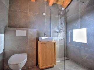 This modern bathroom features a sleek design with gray tiled walls and a glass shower enclosure.