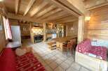This charming cabin-style property boasts a warm and inviting interior with exposed wooden beams and paneling throughout.
