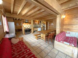 This charming cabin-style property boasts a warm and inviting interior with exposed wooden beams and paneling throughout.