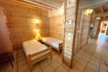 Discover the charm of this cozy bedroom featuring warm wooden walls and two comfortable single beds.