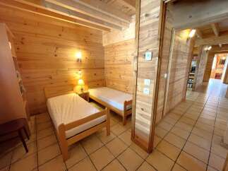 Discover the charm of this cozy bedroom featuring warm wooden walls and two comfortable single beds.