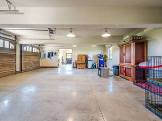 This spacious garage offers ample room for vehicles and storage, featuring a polished concrete floor and overhead lighting.