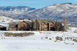 This stunning property boasts a luxurious stone exterior and sits amidst a picturesque winter landscape.