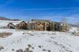 This stunning property showcases a luxurious stone-clad mansion nestled in a serene, snow-covered landscape.