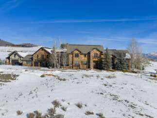 This stunning property showcases a luxurious stone-clad mansion nestled in a serene, snow-covered landscape.