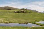 Experience luxurious mountain living in this expansive estate, featuring a stunning main residence and a modern guesthouse nestled on rolling green hills.