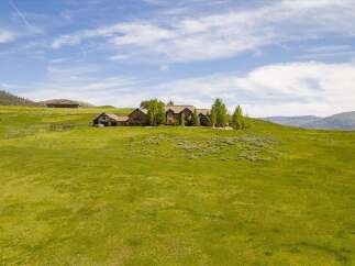 Experience luxury living in this expansive estate, nestled on a sprawling green hillside with breathtaking mountain views.