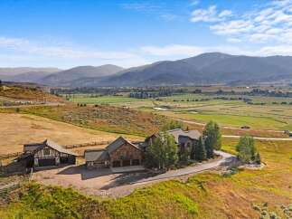 Experience luxury living in this stunning mountain estate, featuring a grand stone-clad residence with multiple garages and a charming guesthouse.