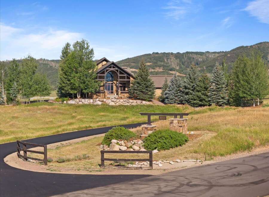 Discover this stunning mountain home, featuring a grand stone exterior and a striking arched entryway with a large glass window.