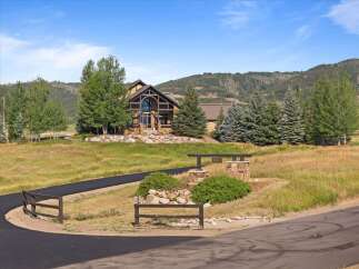 Discover this stunning mountain home, featuring a grand stone exterior and a striking arched entryway with a large glass window.