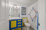This charming bathroom features a unique blue and yellow vanity, adding a pop of color and personality.